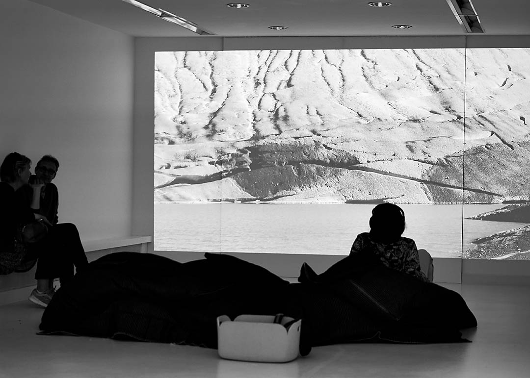 Besucher:innen schauen sich eine Videoinstallation auf einem Beamer an.